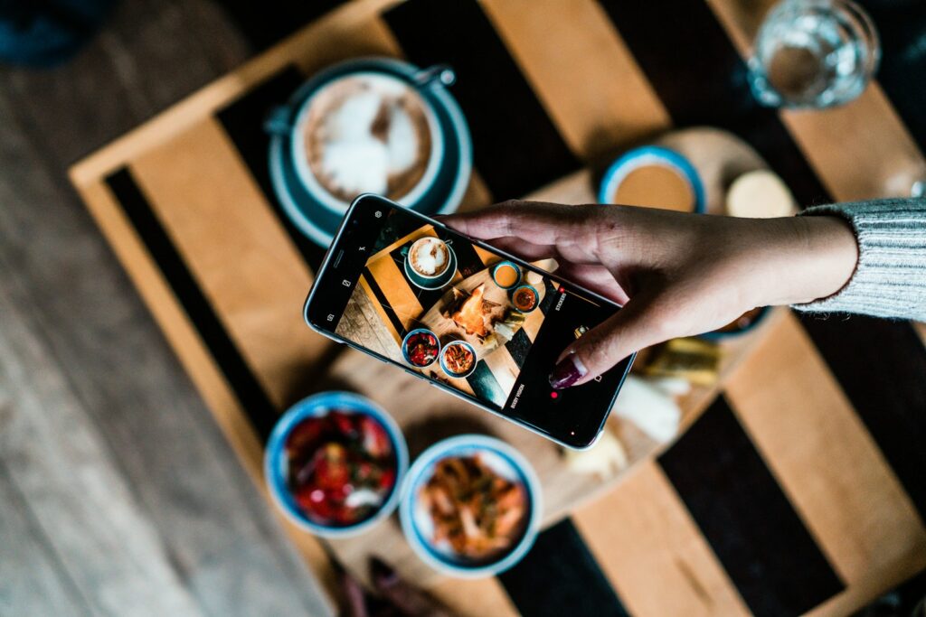 Person photographing food in a cafe with a phone for social media, for a guide to small business social media marketing in Dubai